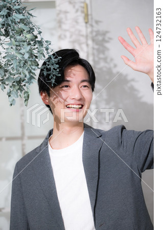 A man wearing a jacket looking up in the shade of a tree, waving while looking up at a meeting A man wearing a jacket looking up in the shade of a tree, waving while looking up at a meeting 124732163