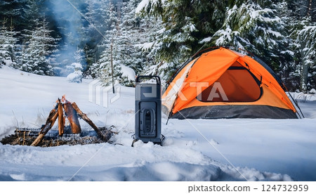 A small campfire is lit in the snow next to a tent A small campfire is lit in the snow next to a tent 124732959