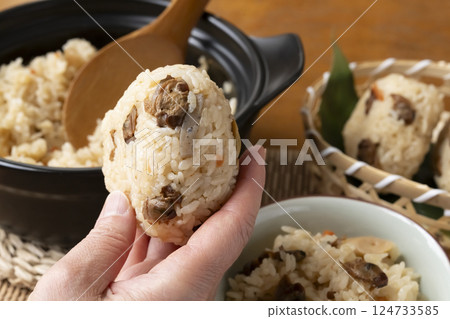 Holding up a clam rice ball in one hand 124733585