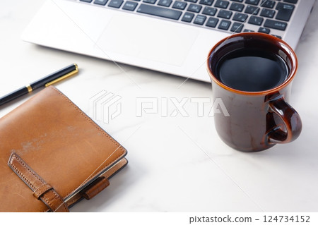 An image of someone working at a desk with a laptop and a personal organizer while drinking freshly brewed delicious coffee An image of someone working at a desk with a laptop and a personal organizer while drinking freshly brewed delicious coffee 124734152