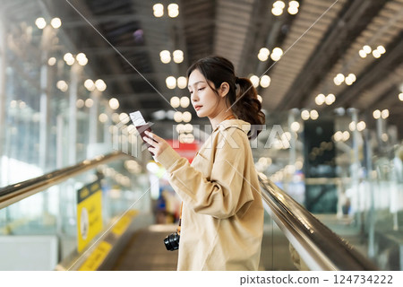 Asia woman commuter travels with luggage on escalator Asia woman commuter travels with luggage on escalator 124734222