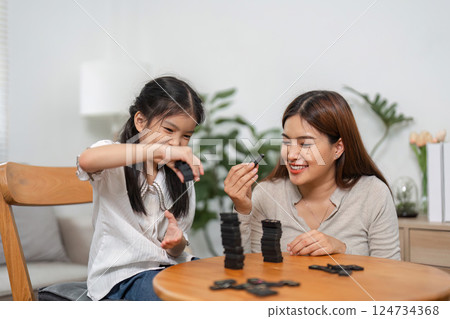 Family Bonding and Gaming. A mother and daughter play a fun domino game together, smiling and enjoying quality time. 124734368