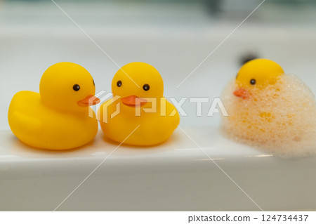 Cheerful and delightful Rubber Ducks floating in a Bathtub filled with soft Bubbles Cheerful and delightful Rubber Ducks floating in a Bathtub filled with soft Bubbles 124734437