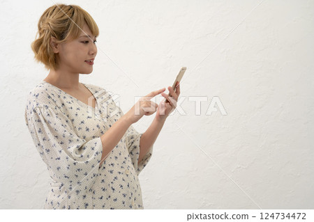 A pregnant woman standing and operating a smartphone 124734472
