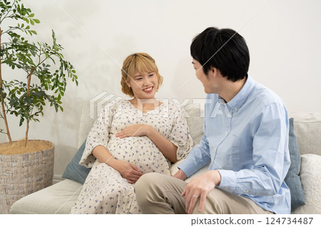 Pregnant couple relaxing in the living room Pregnant couple relaxing in the living room 124734487
