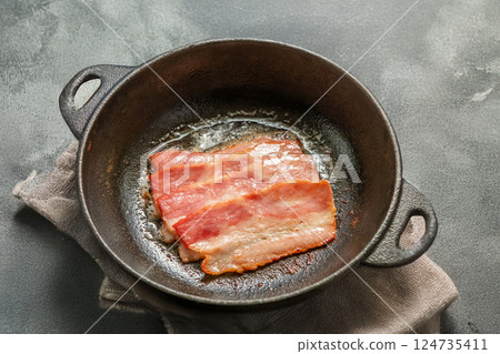 Cook bacon in a cast iron skillet 124735411