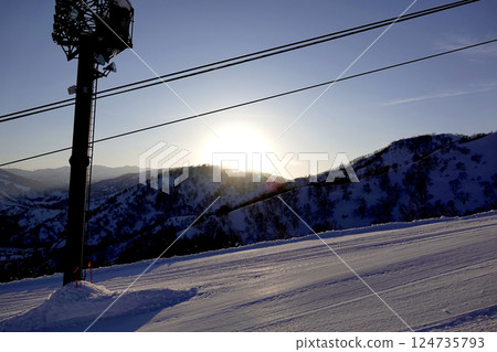Ski resort at sunset. The sun setting behind the mountains and the slopes of the ski slopes. Ski resort at sunset. The sun setting behind the mountains and the slopes of the ski slopes. 124735793