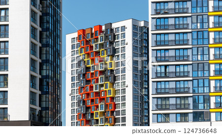 Building with bright facade. Tall high rise apartment with multicolored design, clear blue sky, 124736648