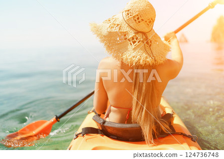 Woman in kayak back view. Happy woman with long hair in a swimsuit and hat floating in kayak on the sea. Summer holiday vacation. Summer holidays vacation at sea. Woman in kayak back view. Happy woman with long hair in a swimsuit and hat floating in kayak on the sea. Summer holiday vacation. Summer holidays vacation at sea. 124736748