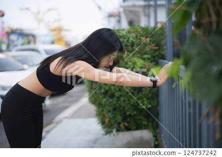 Young Woman Stretching in Urban Environment for Fitness and Wellness, Focused on Health and Exercise with Nature Background in Outdoor Setting 124737242
