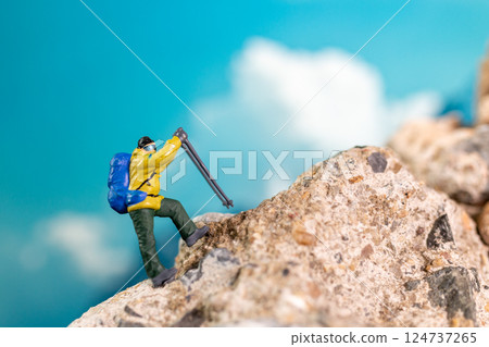 Miniature Climber Reaches Summit Against Majestic Mountain Backdrop 124737265