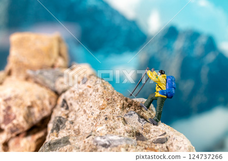Miniature Climber Reaches Summit Against Majestic Mountain Backdrop 124737266