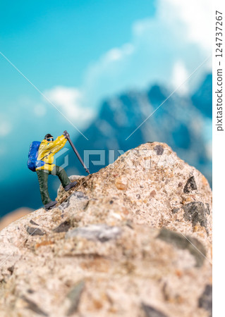 Miniature Climber Reaches Summit Against Majestic Mountain Backdrop 124737267