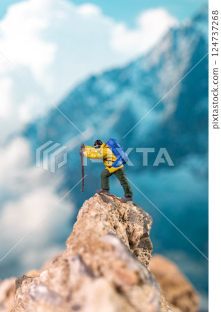 Miniature Climber Reaches Summit Against Majestic Mountain Backdrop 124737268