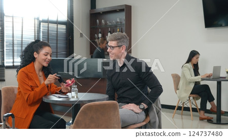 Business man and woman waiting at airport lounge talking together mean boarding pass and passport, Business people while sitting at lobby in convention center wait for their flight at airport terminal Business man and woman waiting at airport lounge talking together mean boarding pass and passport, Business people while sitting at lobby in convention center wait for their flight at airport terminal 124737480