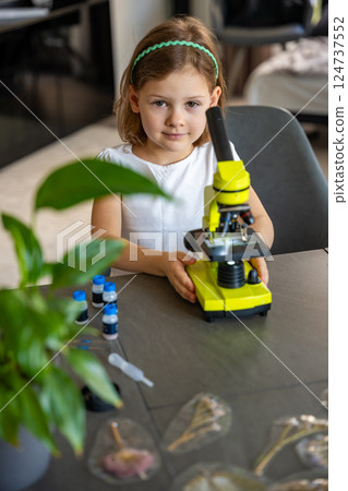 Portrait of little girl with green microscope. Concept of curiosity and early scientific exploration 124737552