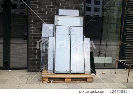 Stack of insulated glass window panes on wooden pallet near modern building facade Stack of insulated glass window panes on wooden pallet near modern building facade 124738354