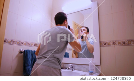 Man removing nose hair with electric trimmer in bathroom mirror Man removing nose hair with electric trimmer in bathroom mirror 124738590