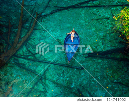 Woman floats on boat in crystal transparent lake with fresh water in Sulawesi. Tourist destination in Indonesia 124741002