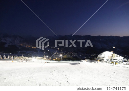 映照著夜燈白光的山坡,在蔚藍的天空映襯下隱約可見的山脊 映照著夜燈白光的山坡,在蔚藍的天空映襯下隱約可見的山脊 124741175