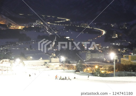 The white reflections of the night lighting on the slopes and the car lights on the road 124741180