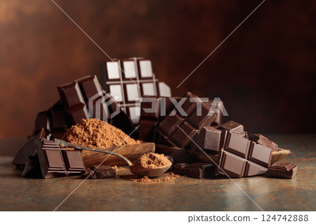 Scraps of dark chocolate next to a wooden bowl of cocoa powder. 124742888