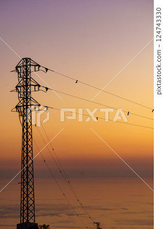 High voltage towers on coast at sunset High voltage towers on coast at sunset 124743330