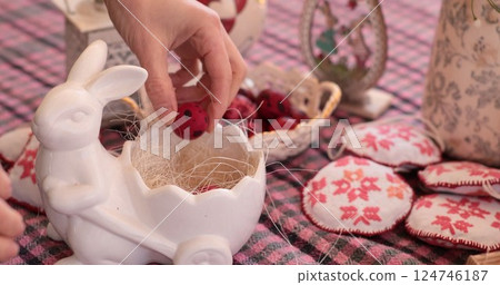 Quail eggs and red Easter eggs placed in a ceramic bunny decoration on a cheerful table setting during a spring celebration 124746187