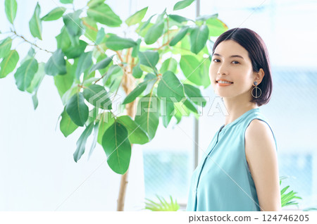 一位穿著夏裝的年輕女子在房間裡操作智慧型手機 124746205