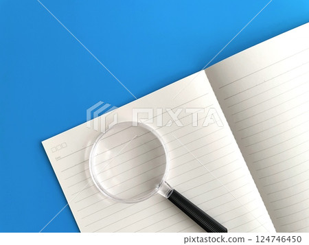 An open notebook and a magnifying glass An open notebook and a magnifying glass 124746450