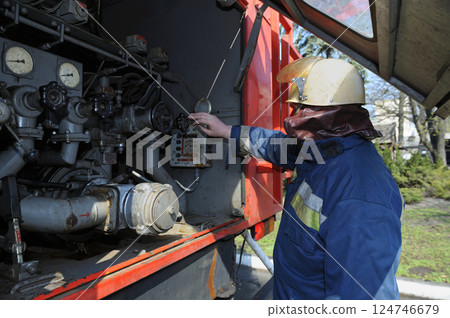 Fireman switching the water pump engine on control panel Fireman switching the water pump engine on control panel 124746679