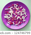 Medicine pills and herbal capsules on a pink plate  124746799