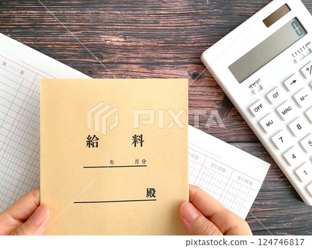 女人的手拿著桌子上的薪水信封 124746817