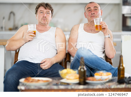 Two adult men drinking beer and watching TV 124746947