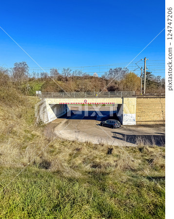 Country Road Car Passing Under Railway Bridge on Clear Sunny Blue Sky Day. High quality photo Country Road Car Passing Under Railway Bridge on Clear Sunny Blue Sky Day. High quality photo 124747206