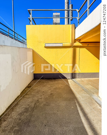 Bright Yellow Wall and Strong Shadows Under Clear Blue Sky in Urban Passageway. High quality photo Bright Yellow Wall and Strong Shadows Under Clear Blue Sky in Urban Passageway. High quality photo 124747208