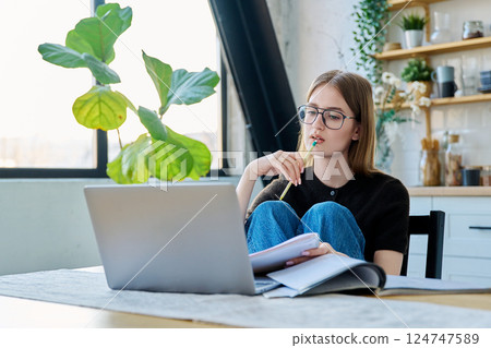 Young woman student studying with laptop sitting at desk, at home Young woman student studying with laptop sitting at desk, at home 124747589