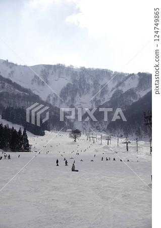 The blue sky is visible through gaps in the thick clouds, and the sun is shining down on the slopes of the ski slopes. The blue sky is visible through gaps in the thick clouds, and the sun is shining down on the slopes of the ski slopes. 124749865