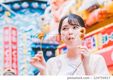 A young woman eating the famous kushikatsu in Shinsekai, Osaka A young woman eating the famous kushikatsu in Shinsekai, Osaka 124750917
