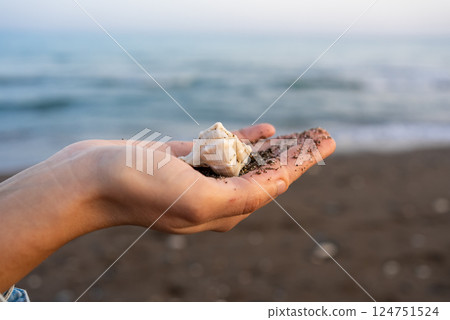 Young woman holding seashell against sea 124751524