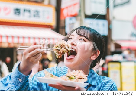 一位女士在大阪道頓堀吃著名的章魚燒 124751548