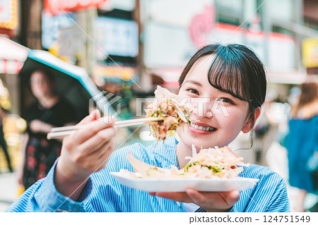 一位女士在大阪道頓堀吃著名的章魚燒 一位女士在大阪道頓堀吃著名的章魚燒 124751549