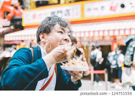 一名中年男子在大阪道頓堀吃著名的章魚燒 124751550