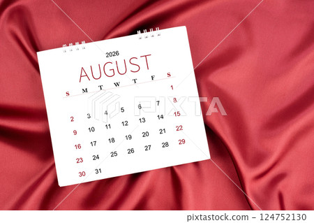 August 2026 Monthly desk calendar on red silk textile background. 124752130