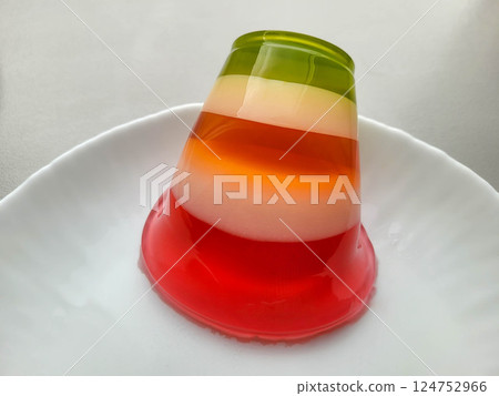 A multi-colored sweet fruit and jelly dessert lies on a white plate. 124752966