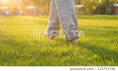 traveler walks barefoot legs on green grass. bare feet stepping on green park enjoying freedom and nature. traveler walks barefoot legs on green grass. bare feet stepping on green park enjoying freedom and nature. 124753786