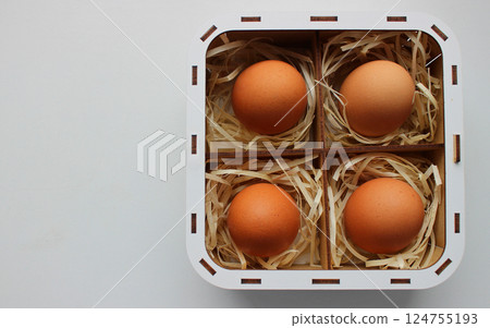 Design for an Easter card featuring brown eggs inside a handmade square wooden basket with compartments filled with delicate shavings 124755193