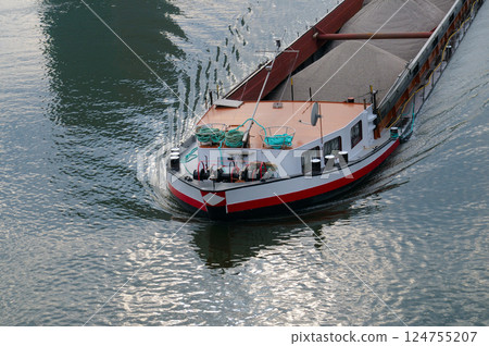 A cargo barge is floating along the river. A cargo barge is floating along the river. 124755207