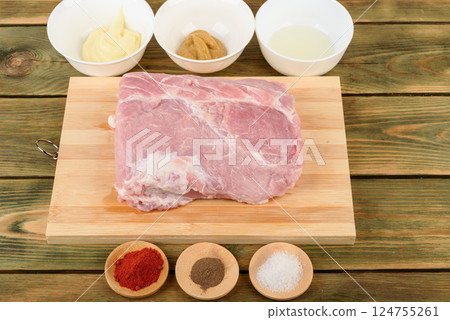Raw pork meat on a cutting board and bowls with spices for marinade. Raw pork meat on a cutting board and bowls with spices for marinade. 124755261