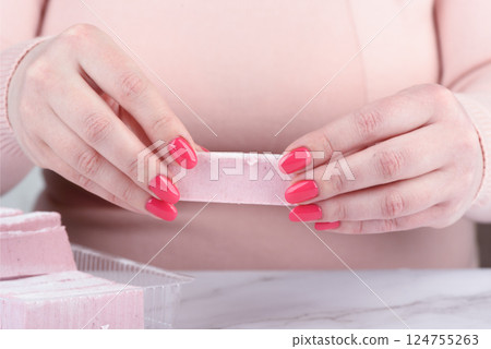 A bar of sweet fruit marshmallow in a girl's hands. A bar of sweet fruit marshmallow in a girl's hands. 124755263
